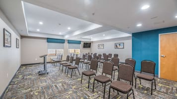 A conference room with rows of chairs, a podium, and a carpeted floor.