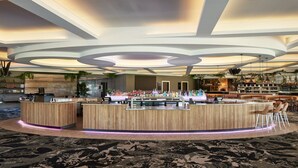 A modern bar area with a central counter, bar stools, and a variety of bottles. - Holiday Inn Warwick Farm by IHG (Cabramatta)