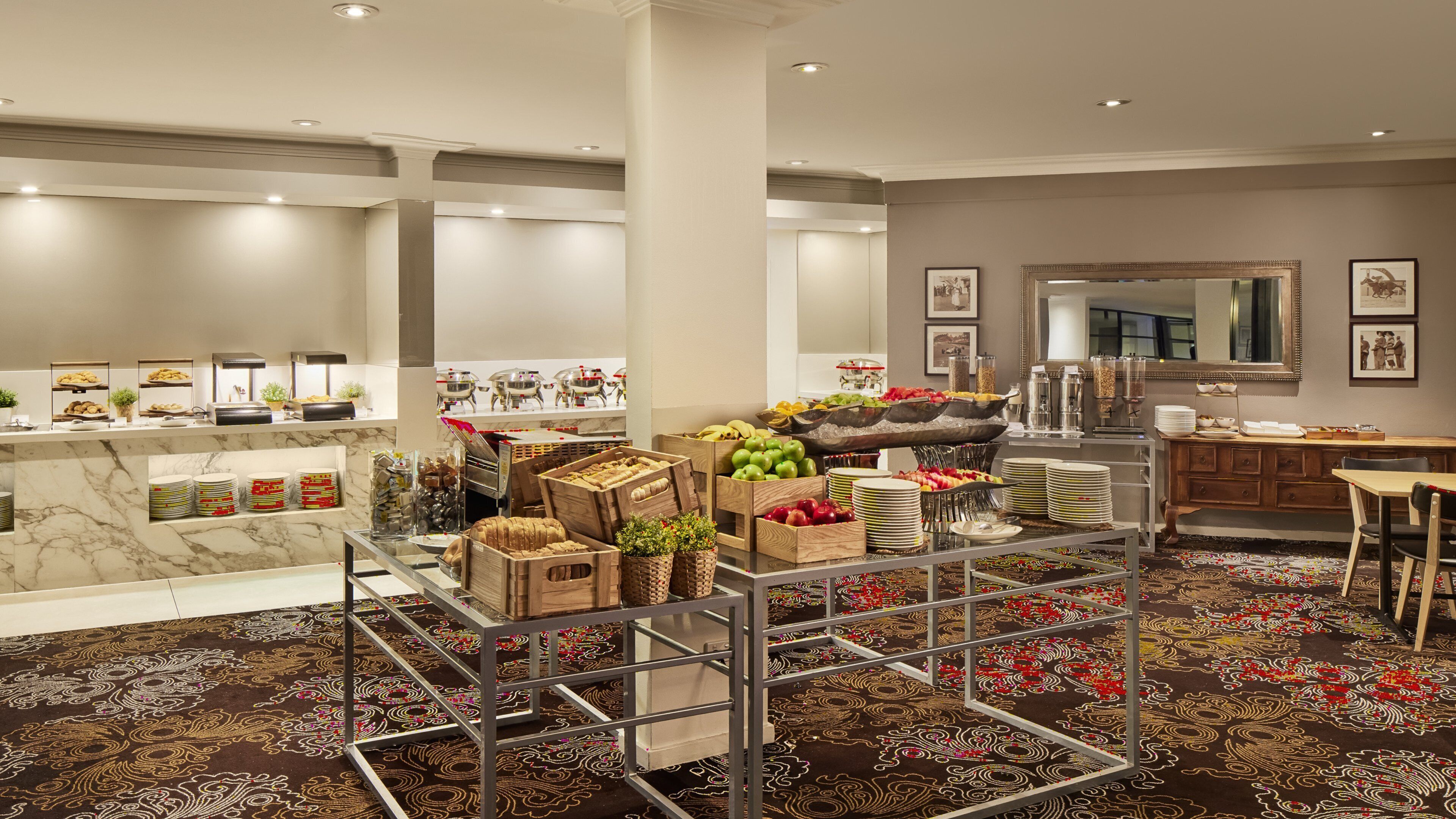 A hotel kitchen with marble countertops, a buffet setup, and a patterned carpet.