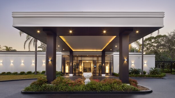 A modern building with a covered entrance, large pillars, and a central decorative urn. - Holiday Inn Warwick Farm by IHG (Cabramatta)