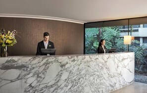 Staff members are available to assist at the reception desk, which offers a view of the surrounding greenery.
