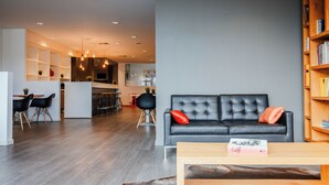 Uma sala de estar moderna com um sofá de couro preto, uma mesa de centro de madeira e uma estante.