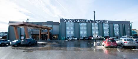 A hotel with a large parking lot and a covered entrance.
