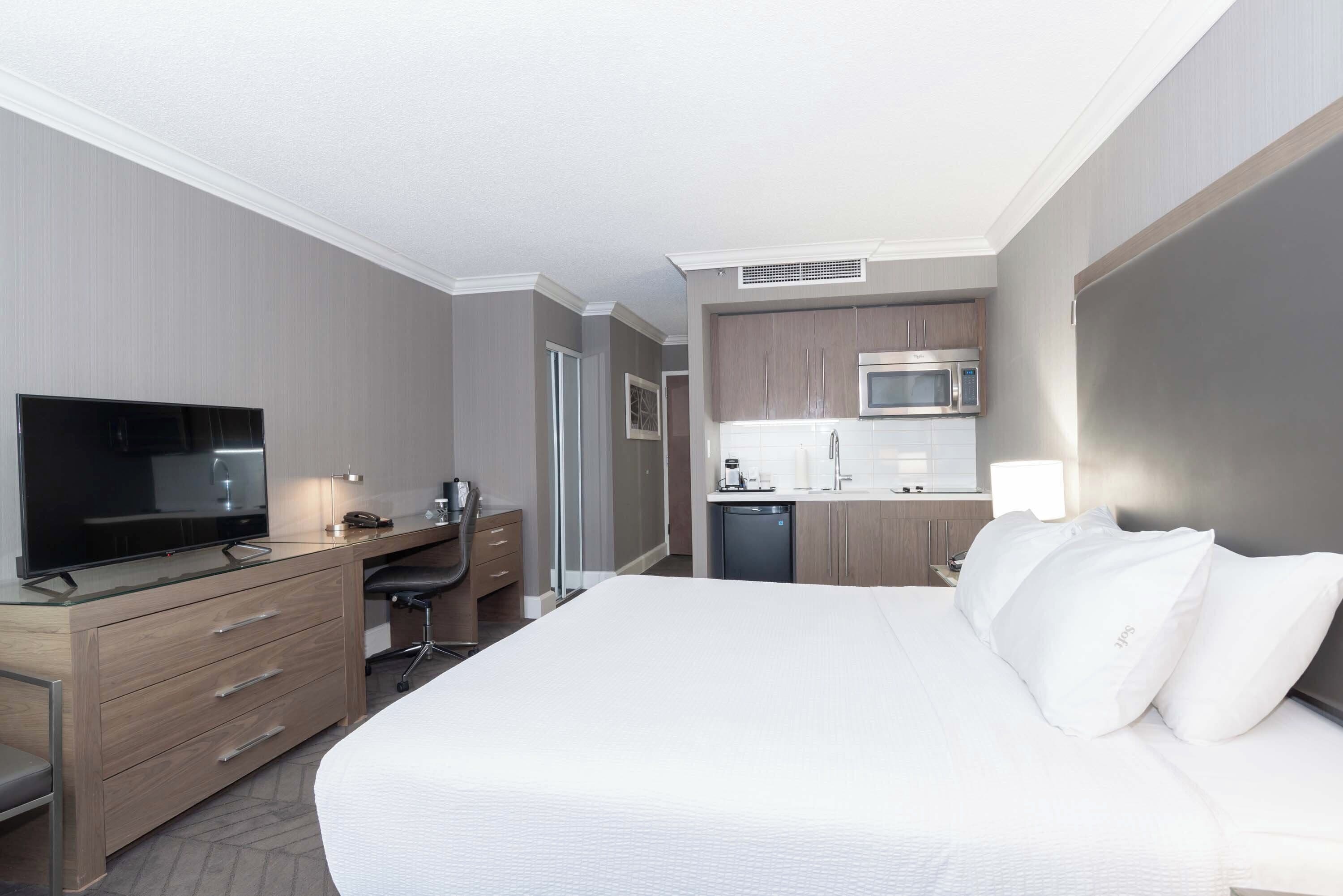 Een hotelkamer met een bed, een bureau met een televisie, een kitchenette en een badkamer.