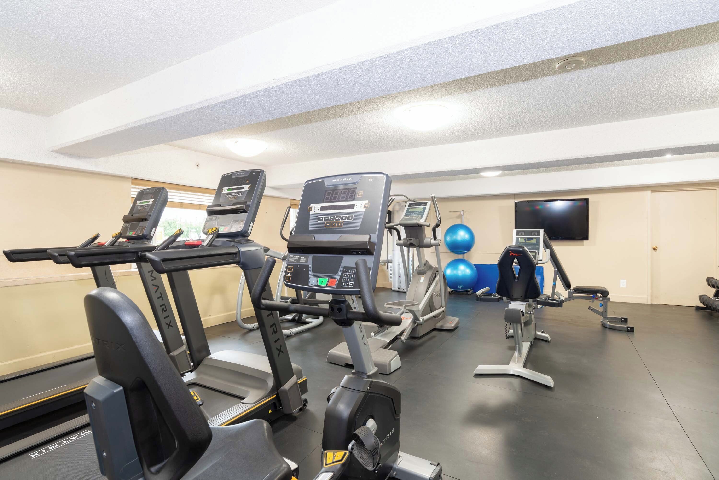 A gym with treadmills, an elliptical, and exercise balls.