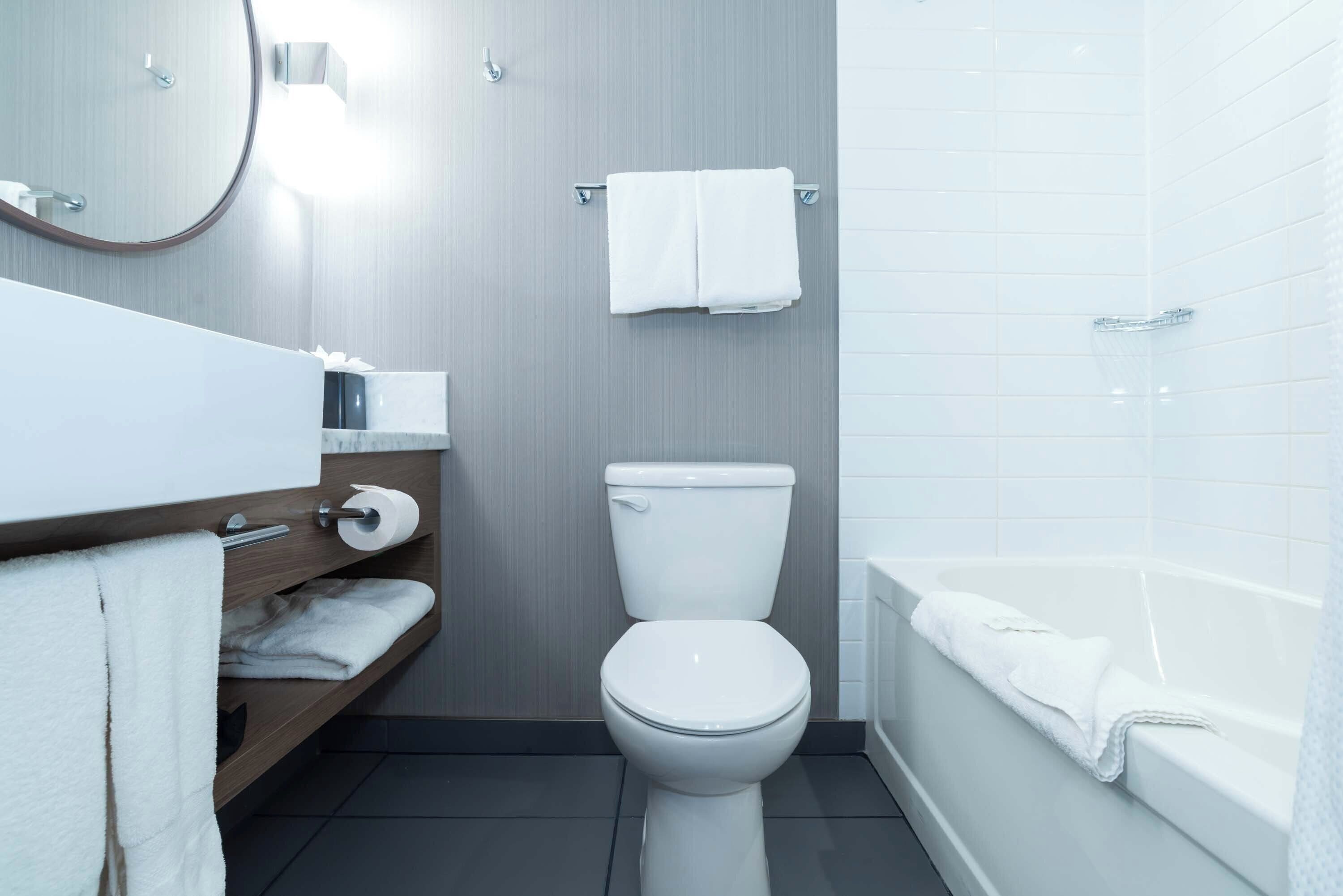 A modern bathroom with a toilet, a sink with a mirror, and a bathtub.