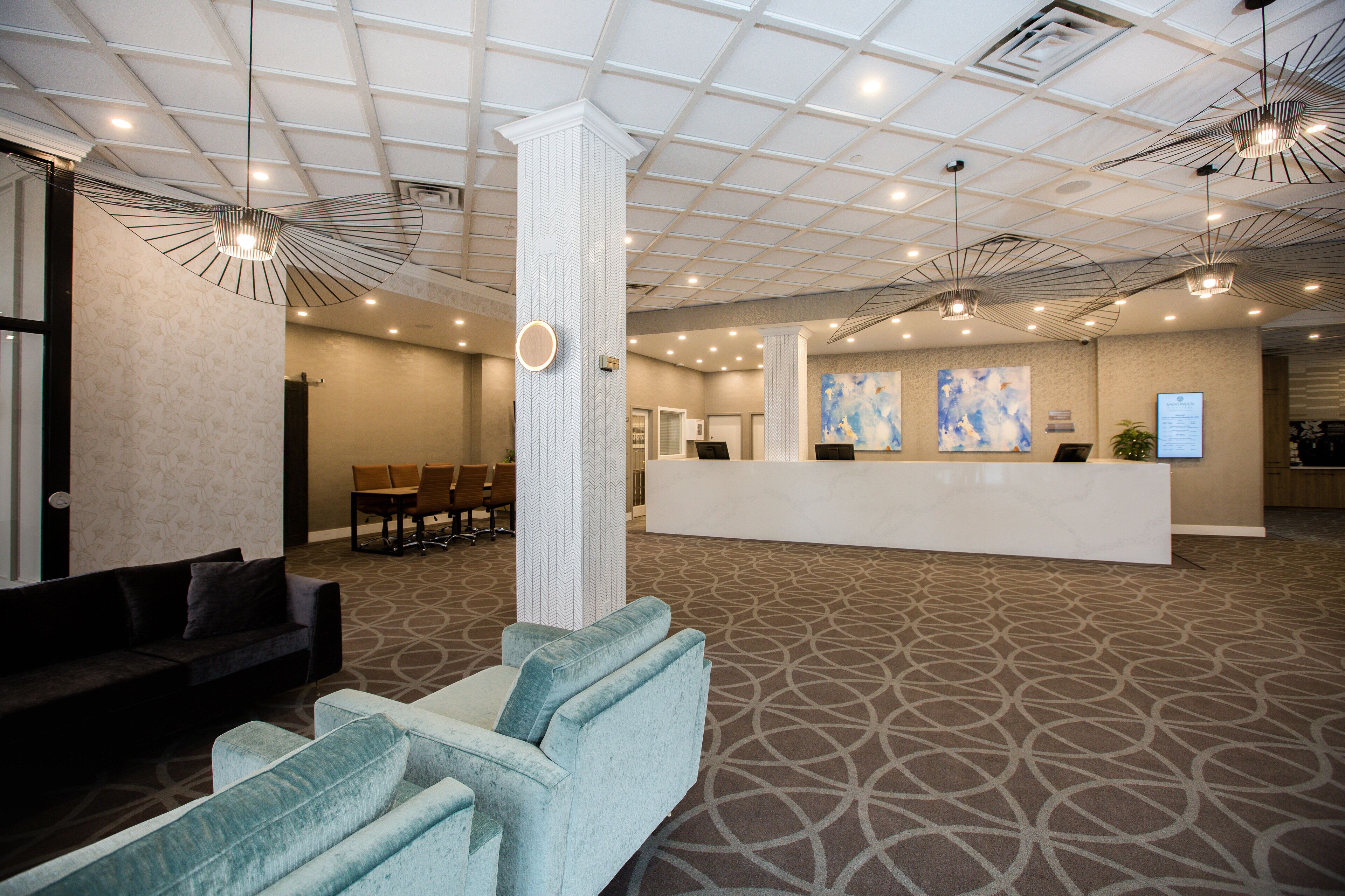 A hotel lobby with a reception desk, seating area, and patterned carpet.