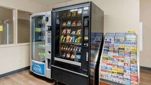 Un distributeur automatique de collations et un réfrigérateur pour les boissons, notamment du Coca-Cola.