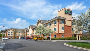 Un hotel con un cartel que dice "extended STAY AMERICA" y un estacionamiento con varios coches.
