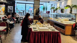 Ein Restaurant mit einem Buffet, Tischen, Stühlen und einer Anrichte mit Speisen.