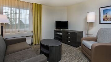 Une chambre d’hôtel équipée d’un canapé, d’une télévision, d’un bureau, d’une lampe et d’un tableau encadré au mur.