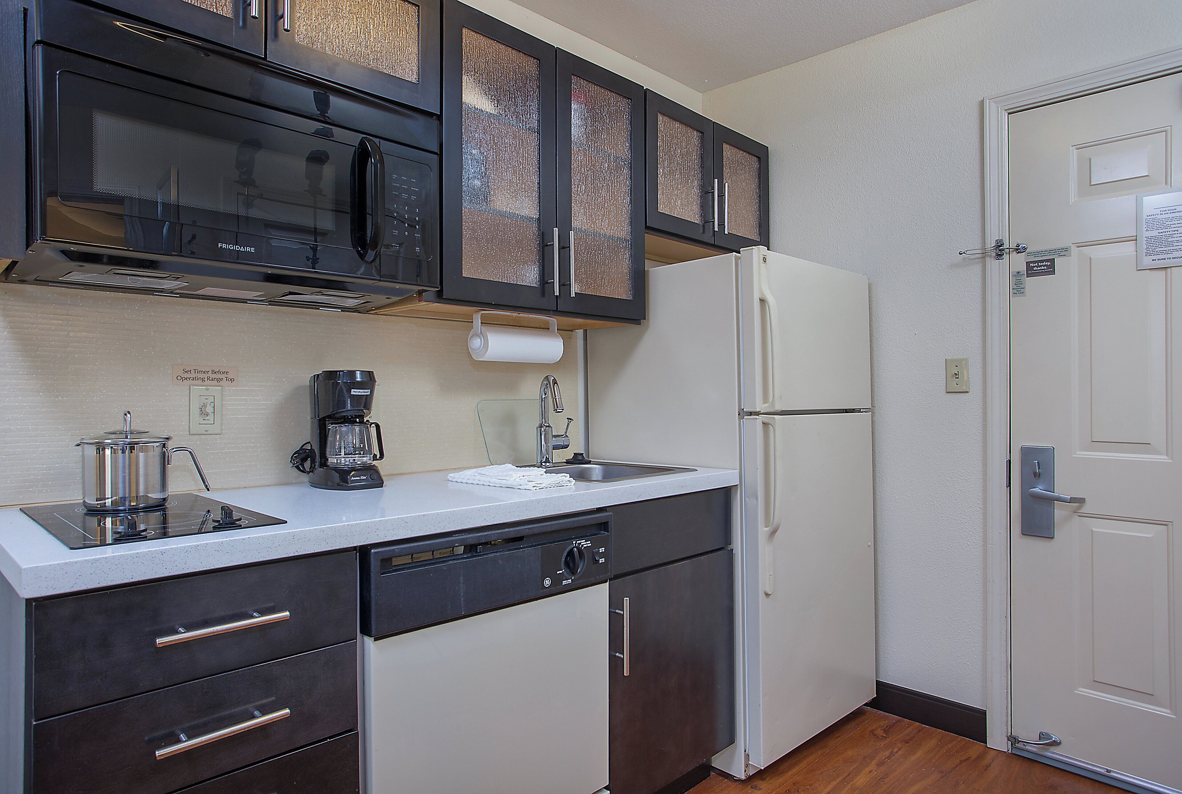 A compact kitchen with a microwave, coffee maker, and a refrigerator.