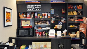 A Candlewood Cupboard with a variety of snacks, beverages, and a microwave.