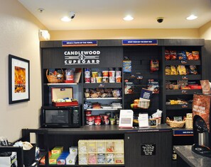A Candlewood Cupboard with a variety of snacks, beverages, and a microwave. - Candlewood Suites Louisville Airport by IHG (Louisville)