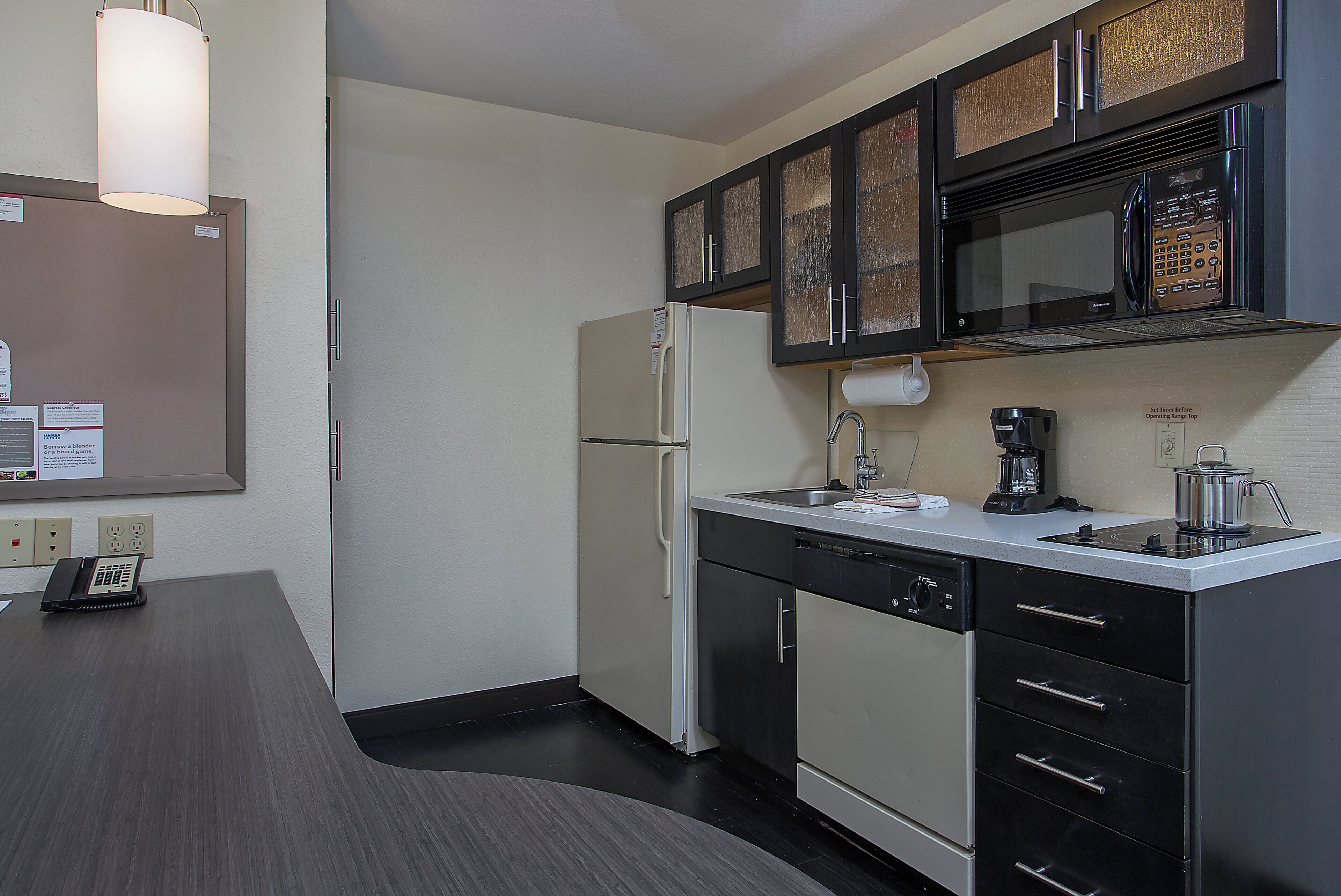A modern kitchen with a refrigerator, microwave, coffee maker, and a sink.