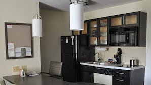A modern kitchen with a central island, black cabinetry, a microwave, and a coffee maker.