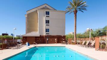 Een buitenzwembad, ligstoelen bij het zwembad