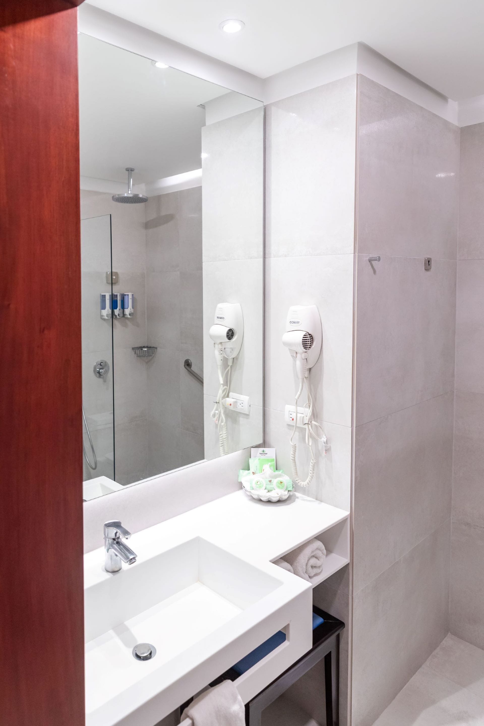 A modern bathroom with a large mirror, a white sink, and a shower area.