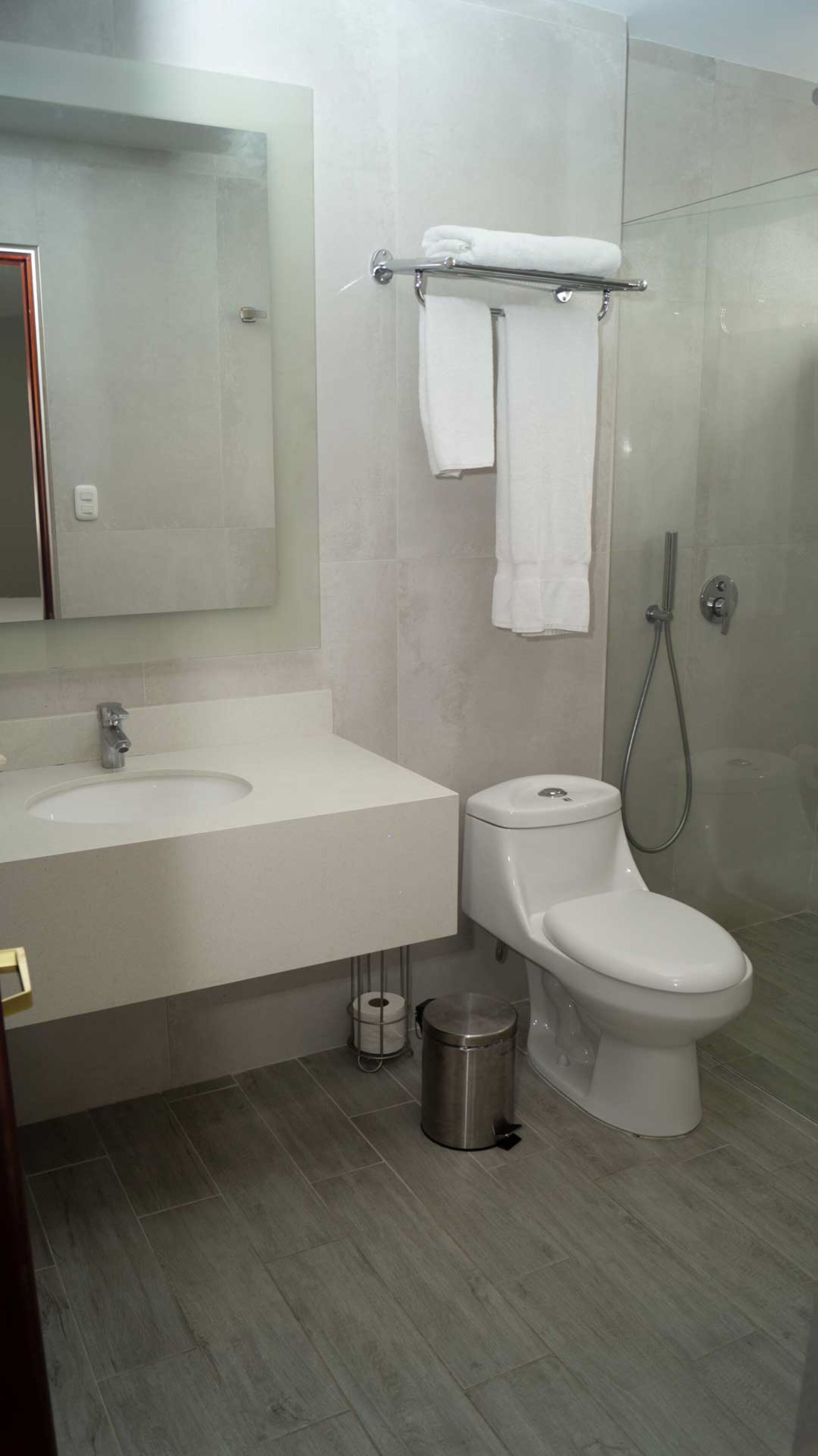 A modern bathroom with a white sink, toilet, and shower.