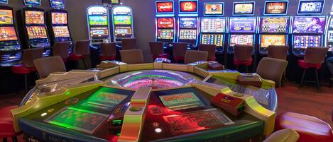 Un casino con máquinas tragamonedas y una mesa de juego central.