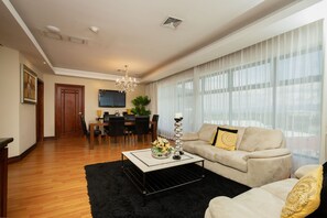 A modern living room with a sofa, coffee table, and a dining area with chairs and a TV. - Hotel Palma Real (San José)