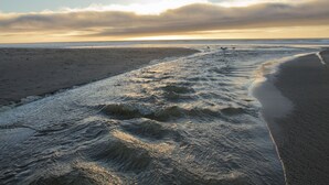 A beach with waves and a clear sky.