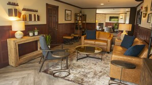 A cozy living room with a leather sofa, a glass coffee table, and a wooden console table with a lamp.