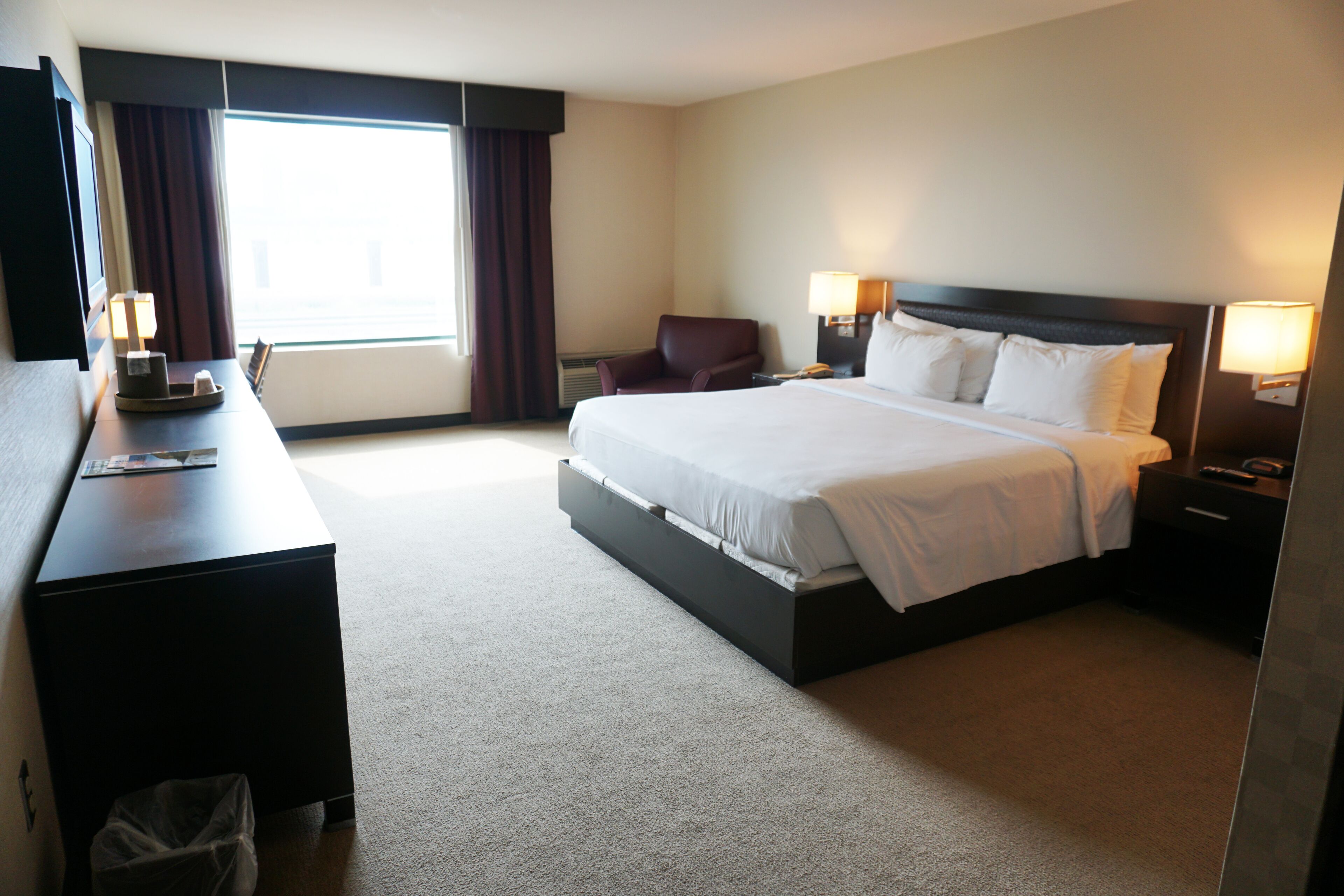A hotel room with a large bed, a desk, a chair, and a TV.