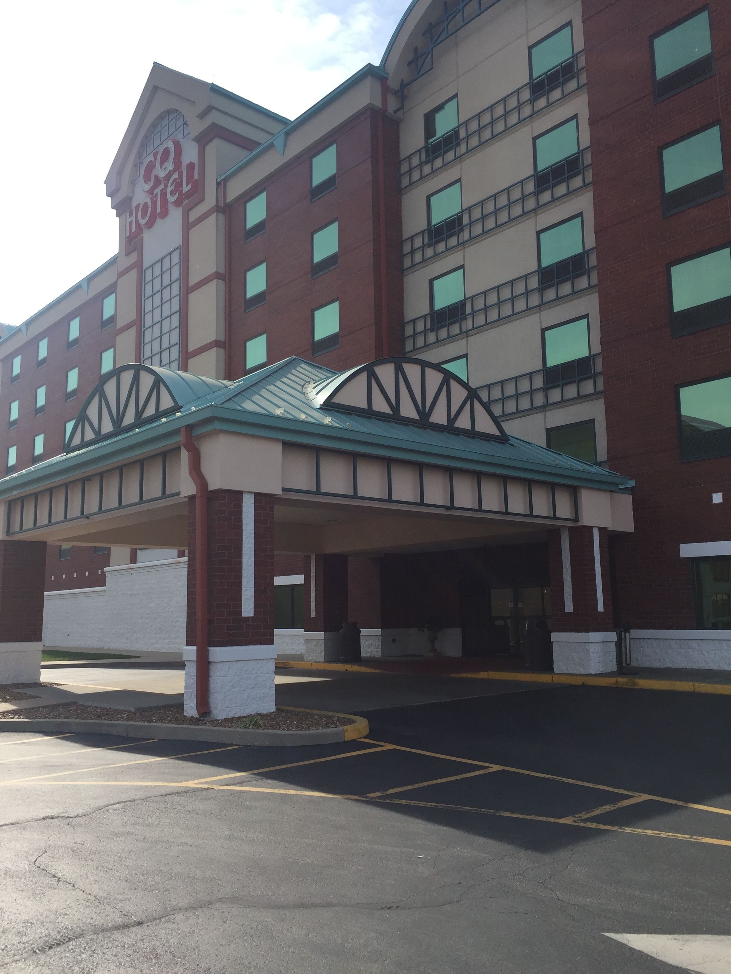 A hotel with a covered entrance, multiple floors, and a parking lot.