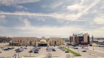 En stor bygning med en central kuppel og buede vinduer, omgivet af en parkeringsplads og en bro i baggrunden.