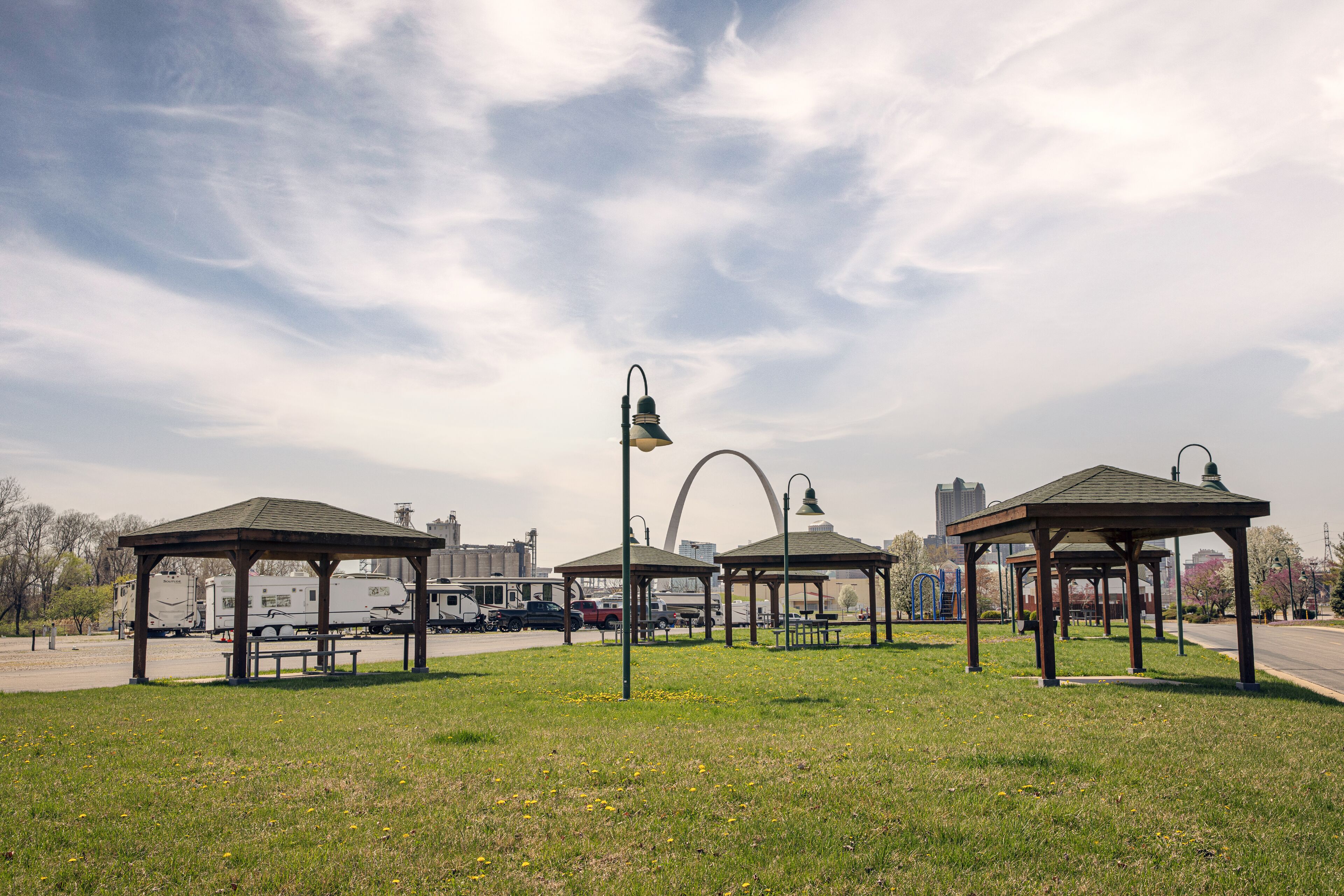 Un parc doté de plusieurs kiosques, de bancs et d’un lampadaire.