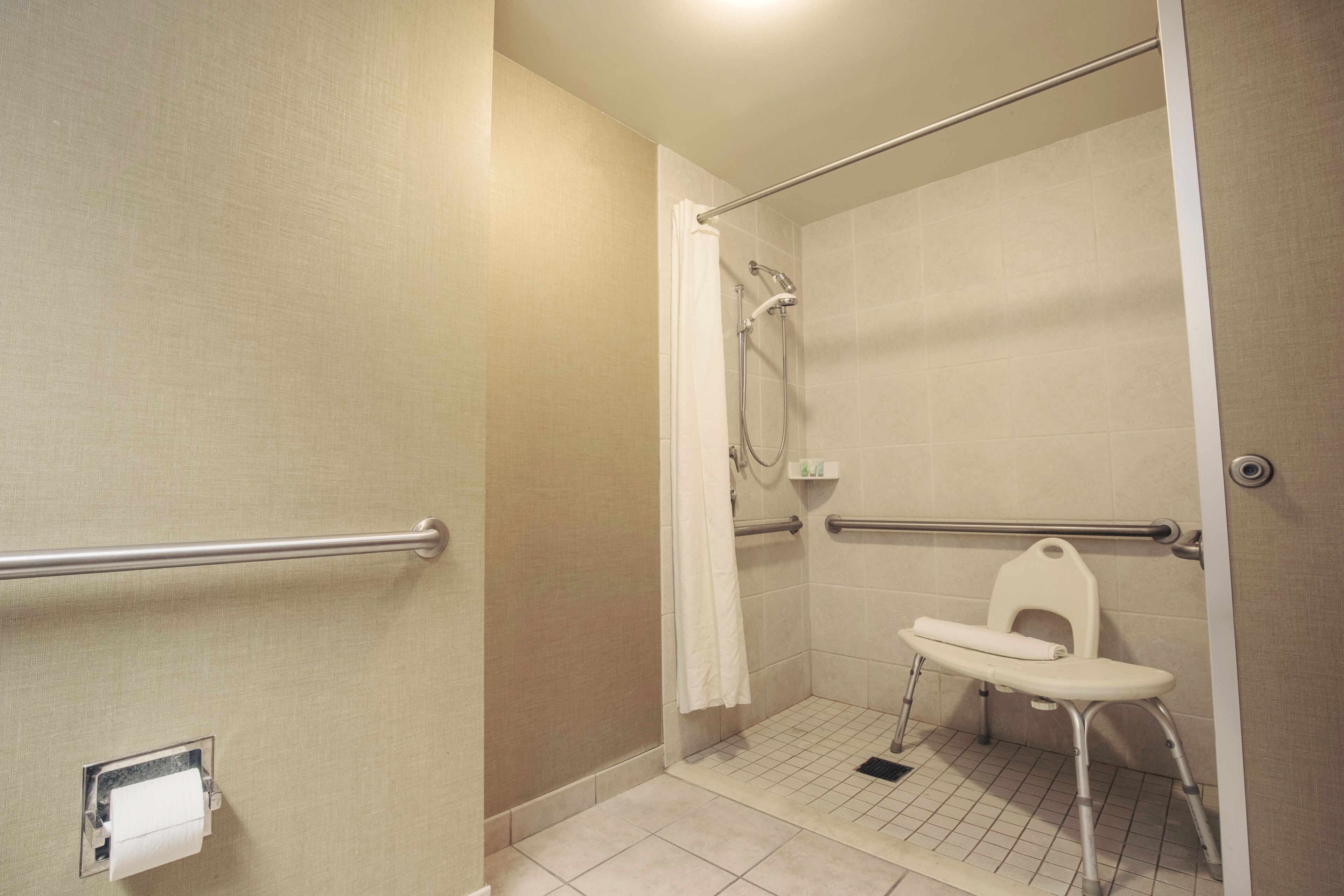 A bathroom with a shower, a toilet, and a grab bar.