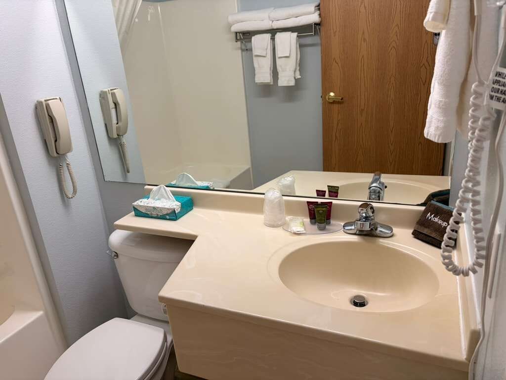 Ein Badezimmer mit Waschbecken, Toilette und zwei an der Wand befestigten Telefonen.