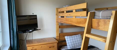 A bunk bed with a TV mounted on a wooden dresser below.