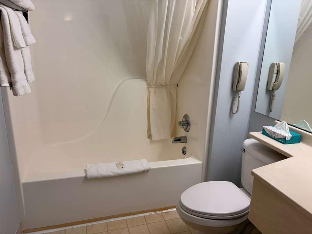 A bathroom with a bathtub, toilet, and a sink with a mirror.