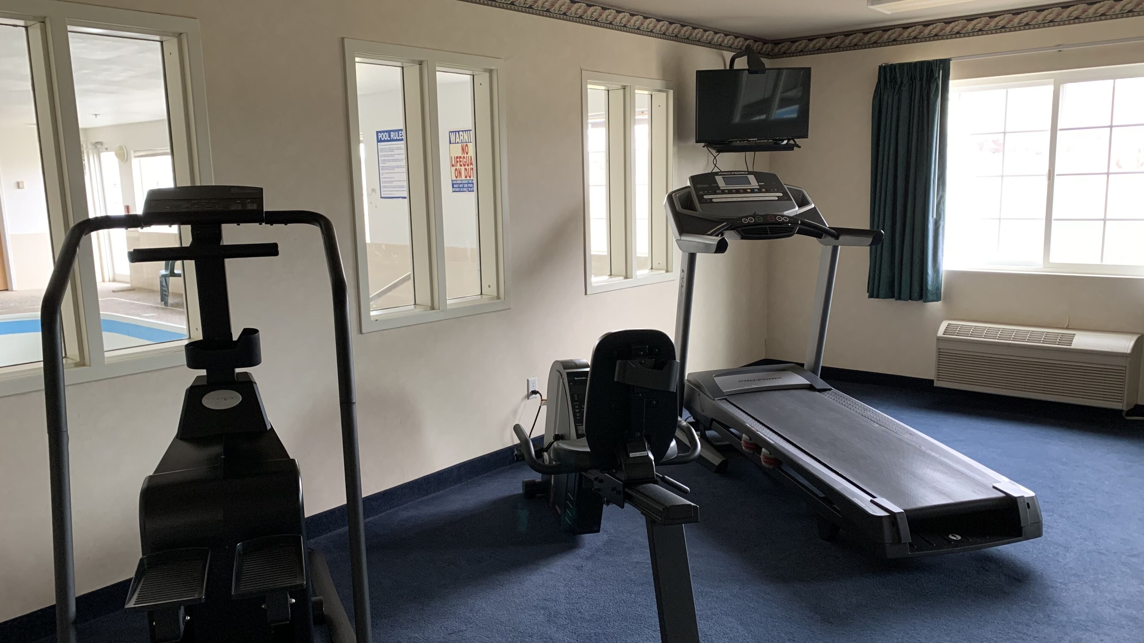 A fitness room with a treadmill, elliptical, and stationary bike.