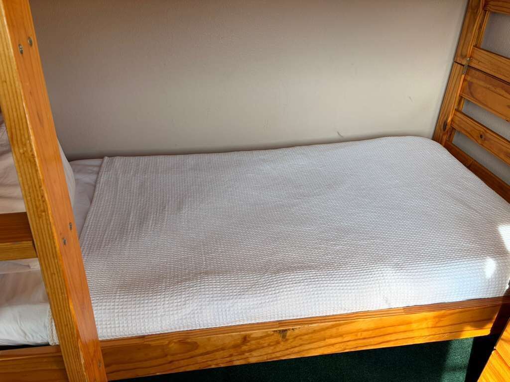 A bunk bed with a white mattress and wooden frame.