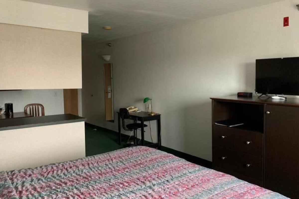 A hotel room with a bed, a desk, a television, and a wardrobe.