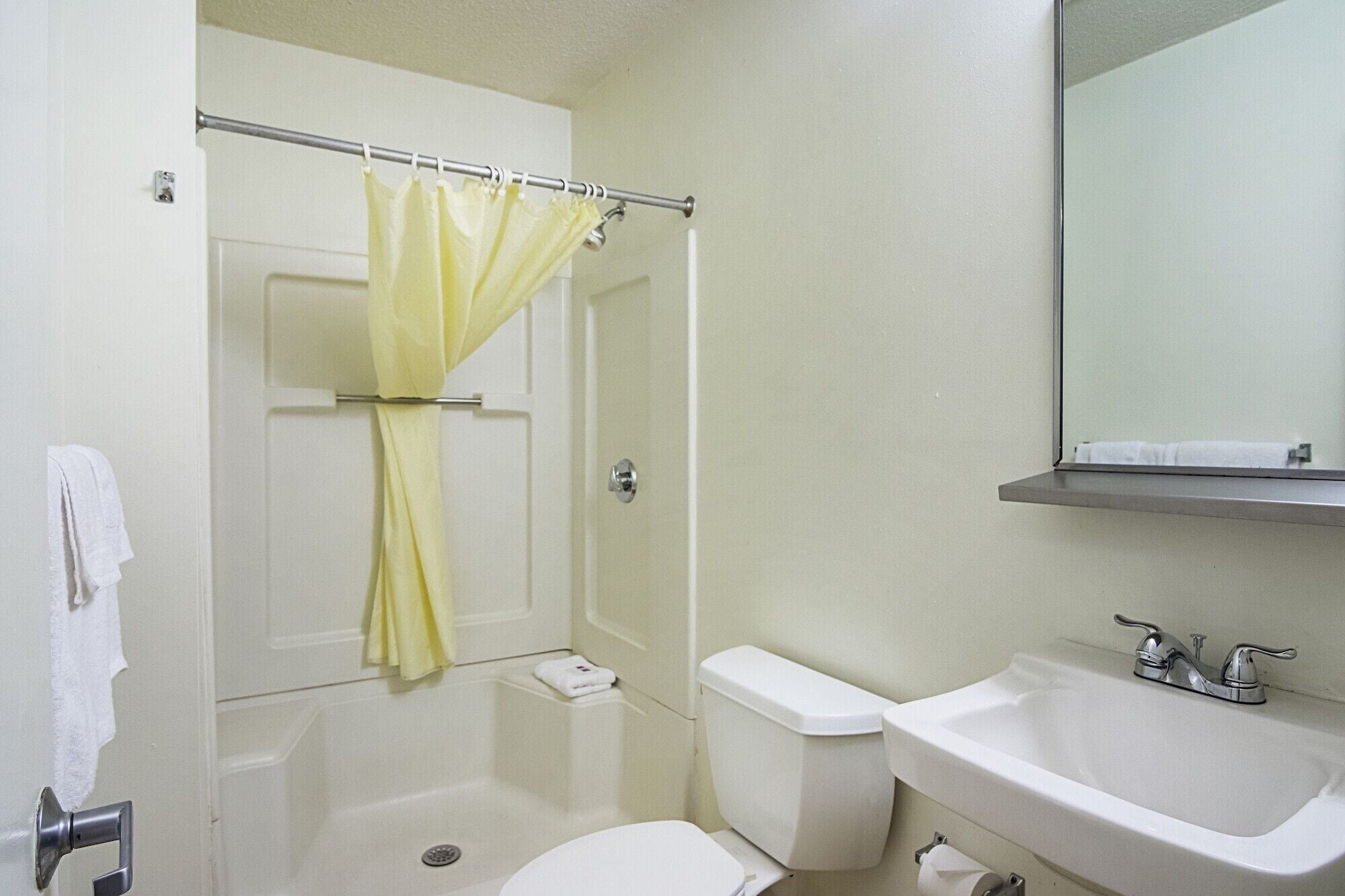 Un baño con cortina de ducha, inodoro, lavabo y espejo sobre el lavabo.