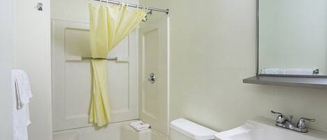 Un baño con cortina de ducha, inodoro, lavabo y espejo sobre el lavabo.