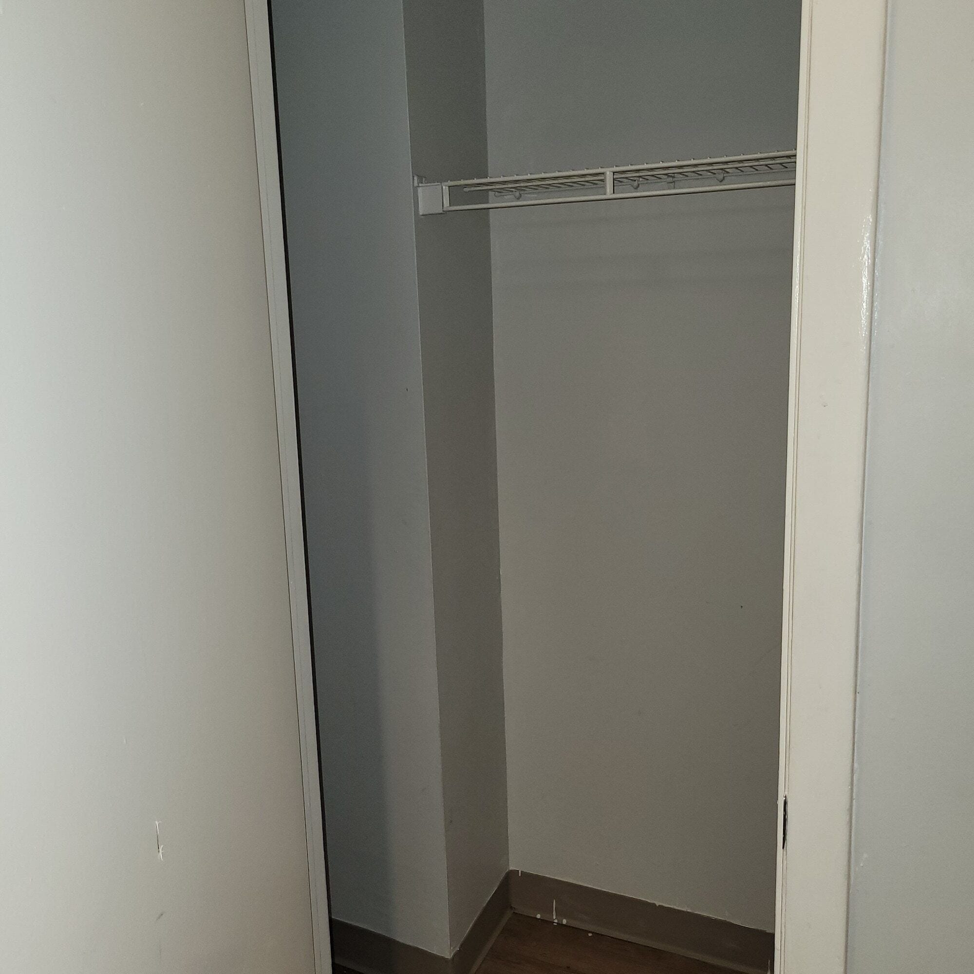 A closed closet with a metal rod shelf.