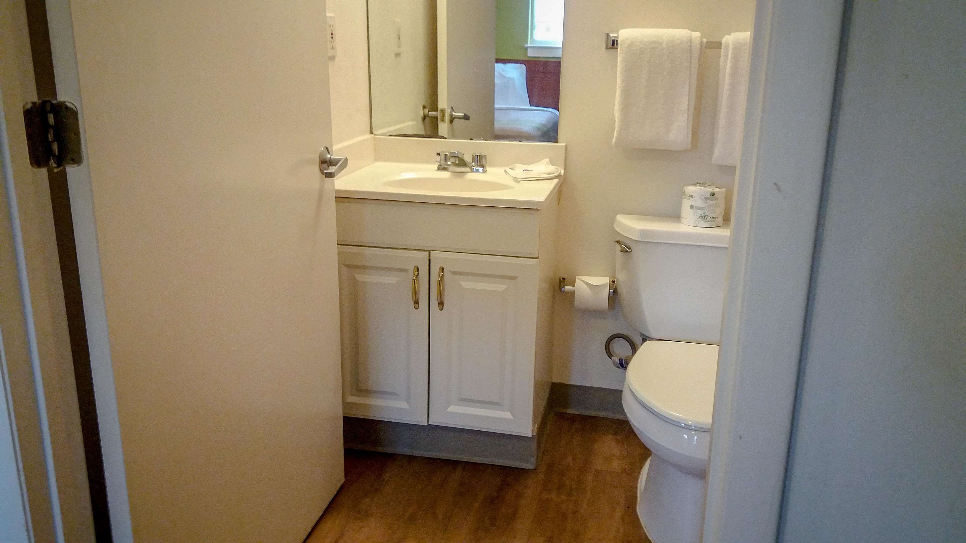 Une salle de bain avec un lavabo blanc, un miroir et des toilettes.