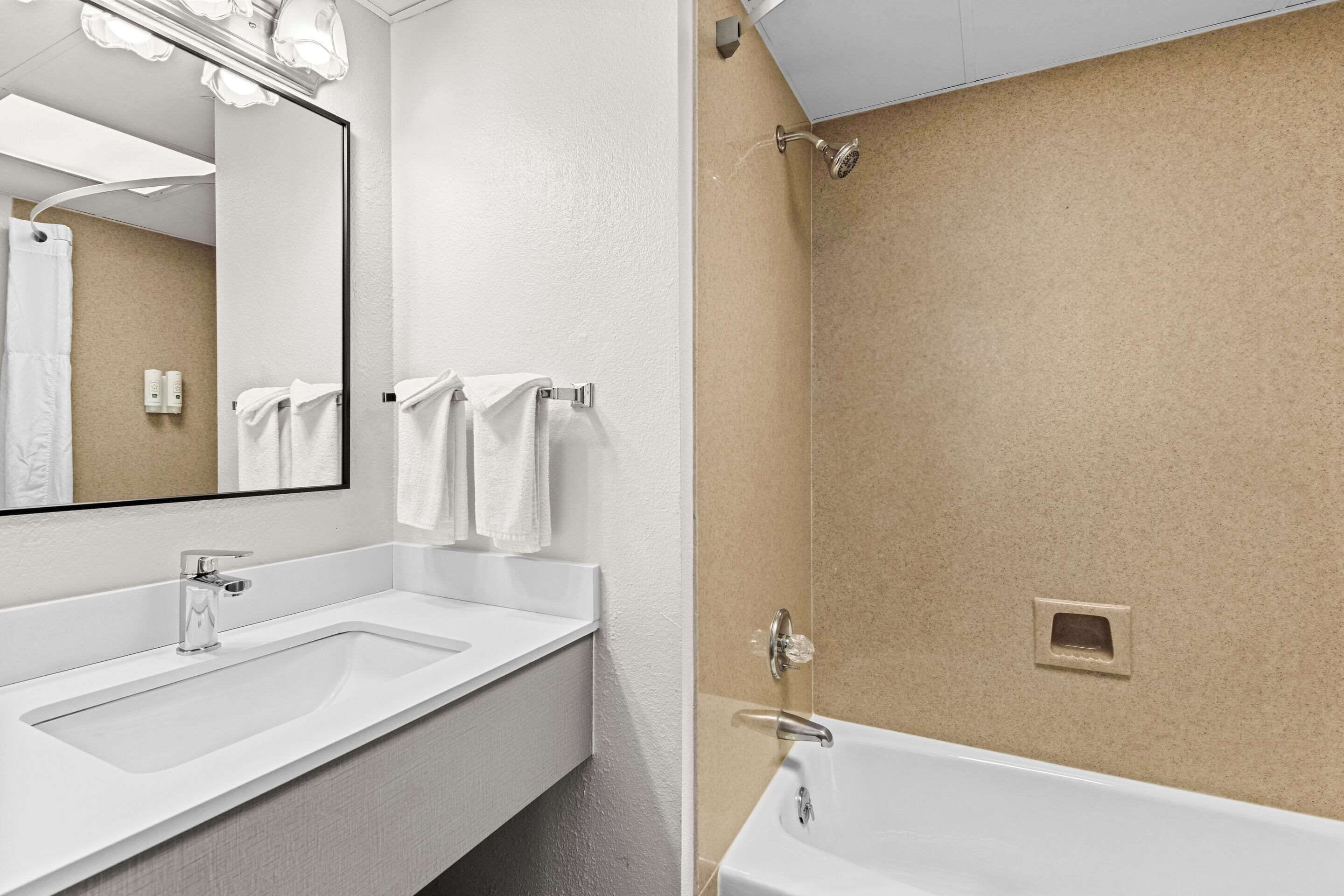 A modern bathroom with a large mirror, two sinks, and a shower area.