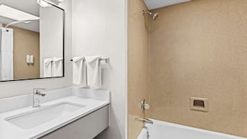 A modern bathroom with a large mirror, two sinks, and a shower area.