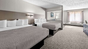 Habitación de hotel con dos camas, un espejo grande, un escritorio y vistas al exterior.