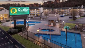 Un hotel con un cartel de 'Quality Inn & Suites by Choice Hotels', que presenta un área de piscina con varias piscinas y una terraza con cerramiento.