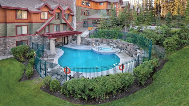 A large house with a swimming pool surrounded by a fence, a hot tub, and a covered patio area. - WorldMark Canmore - Banff (Canmore)