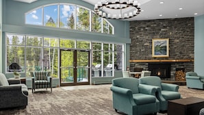 A spacious living room with large windows, a stone fireplace, and comfortable seating. - WorldMark Canmore - Banff (Canmore)