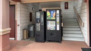 A vending machine with a selection of beverages and a fire alarm panel. - Red Roof Inn Virginia Beach - Norfolk Airport (Virginia Beach)