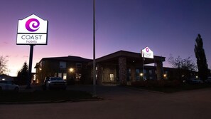 Hotel amb façana de pedra, diverses finestres i un pàrquing.